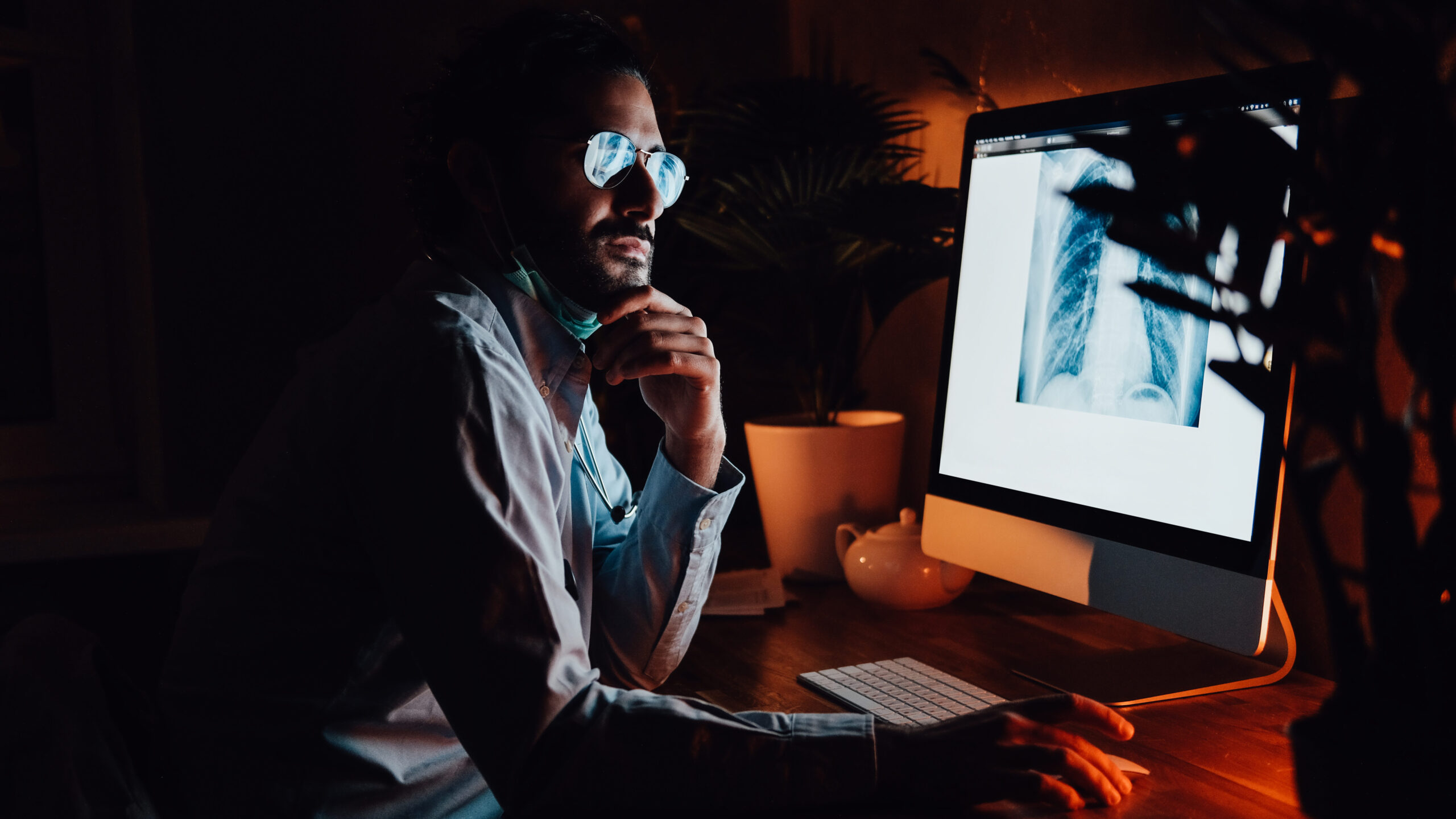 Healthcare professional in a dark room looks at medical images.